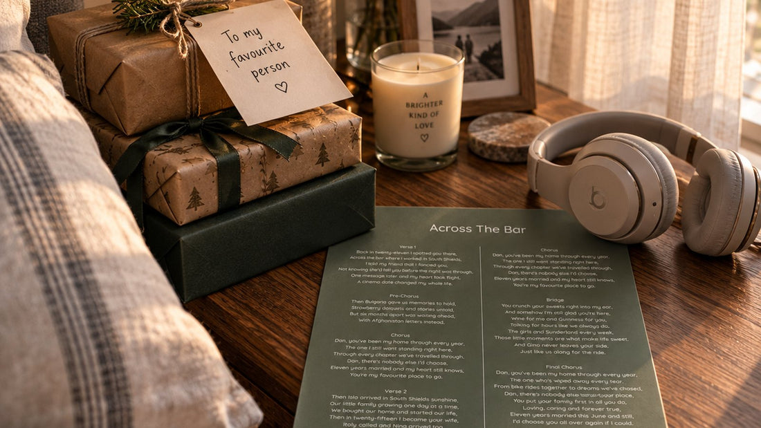 Wrapped gifts, a candle, headphones and a personalised song lyric sheet on a bedside table in morning light