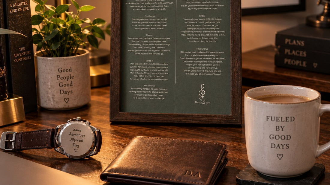 A framed personalised song lyric sheet on a desk with a watch, wallet and coffee mug