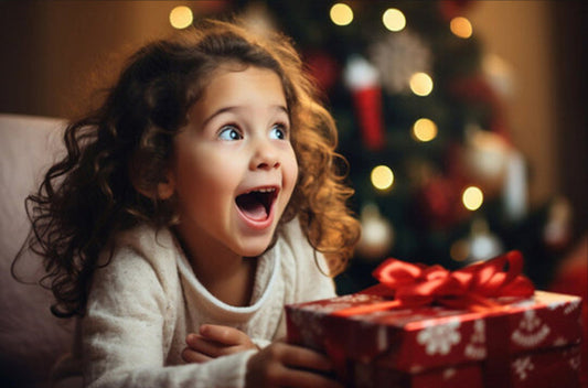 Child with a surprised expression holding a Christmas gift in front of a decorated tree, with text 'Create Your Child's Christmas Song'.